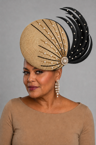 Woman wearing a natural straw statement hat trimmed with black feathers, black beading, and pearl detailing.